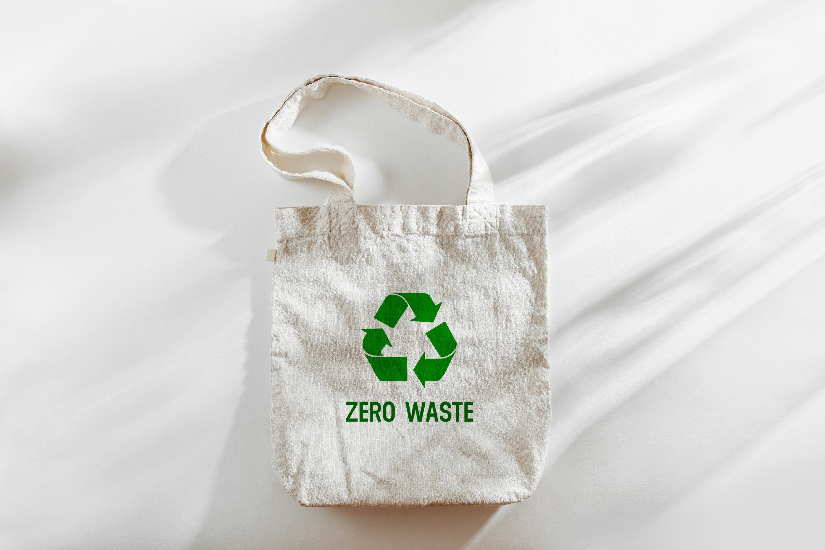 A reusable cotton tote bag with a green recycling symbol and "Zero Waste" text, promoting sustainability and eco-friendly living.